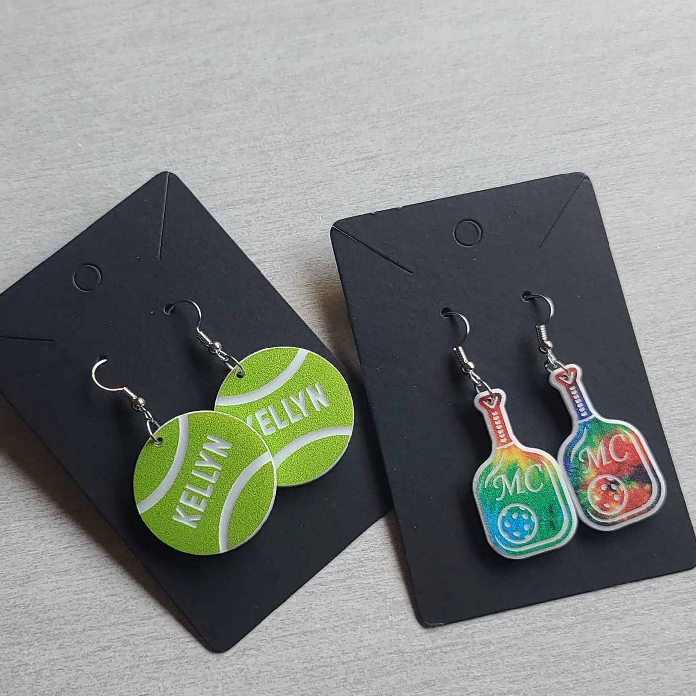 Tennis ball and colorful guitar earrings on black display cards